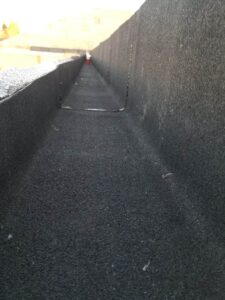 Silverback Torch On Systems Ltd. applying primer to commercial flat roofing deck as part of the torch-on membrane process